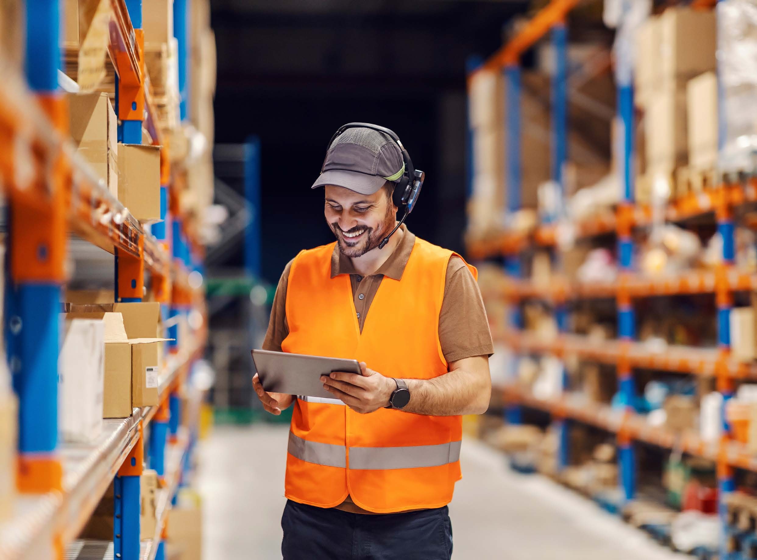 Warehouse worker with a tablet in front of pallet racking