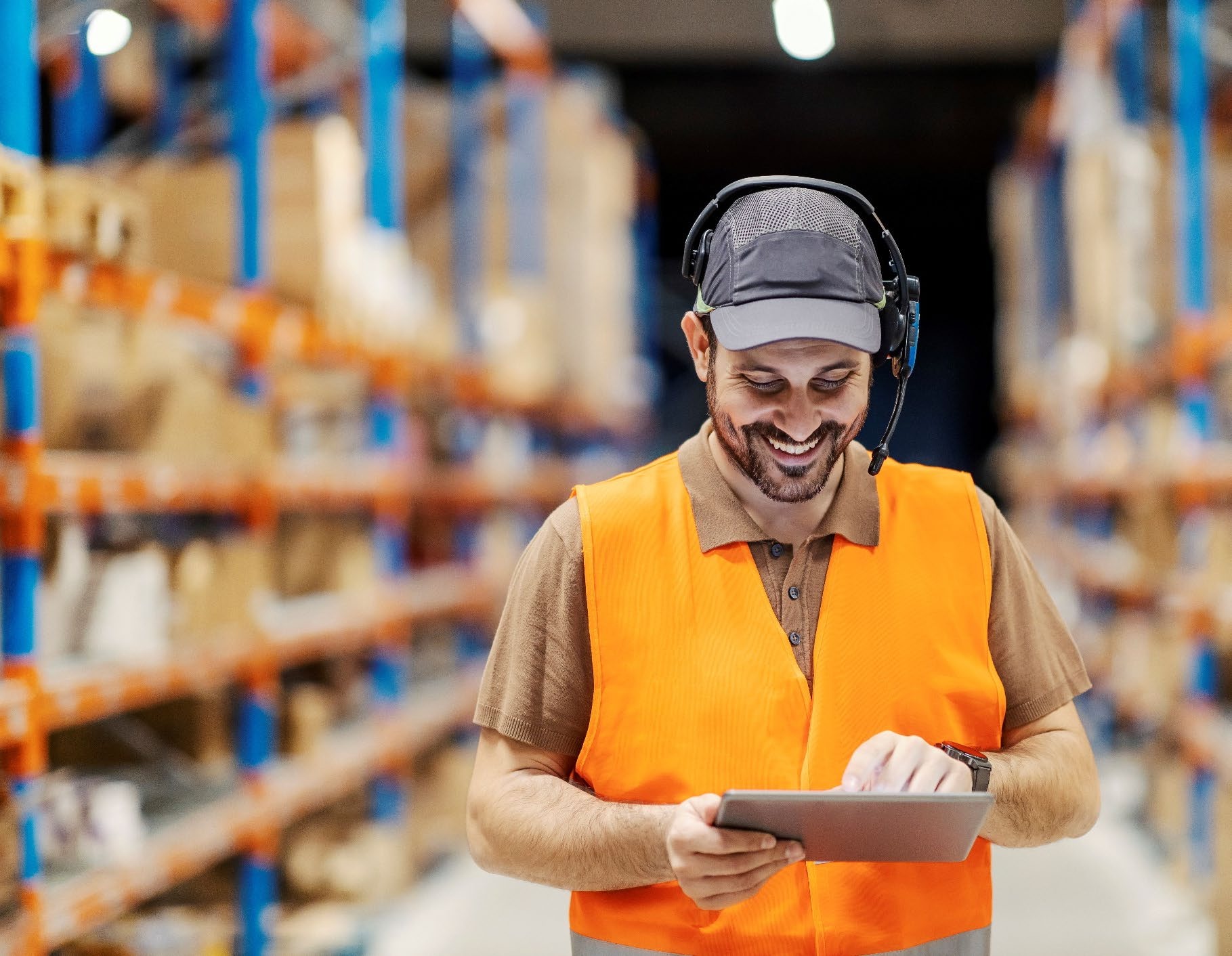 Warehouse worker smiling while checking stock on a tablet